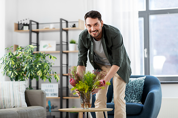 Image showing man placing flowers on coffee table at home