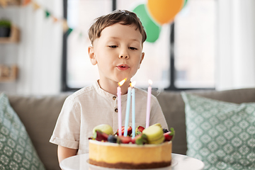 Image showing happy little boy blowing candles on birthday cake