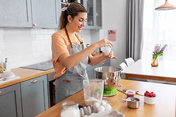 Image showing happy young woman cooking food on kitchen at home