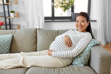 Image showing happy pregnant asian woman sitting on sofa at home