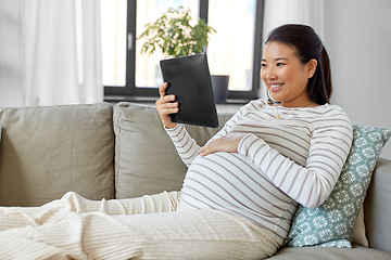 Image showing happy pregnant asian woman with tablet pc at home