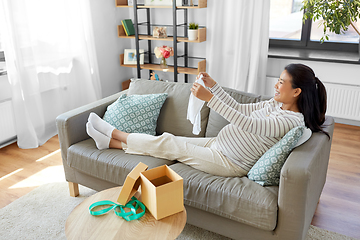 Image showing happy pregnant woman with baby's bodysuit at home