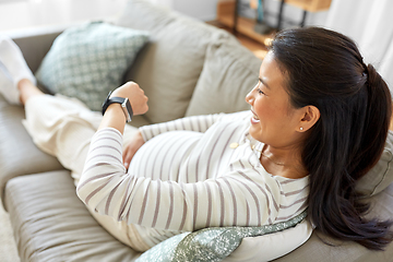 Image showing happy pregnant woman with smart watch at home