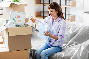 Image showing happy woman unpacking boxes and moving to new home