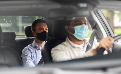 Image showing male driver in mask driving car with passenger