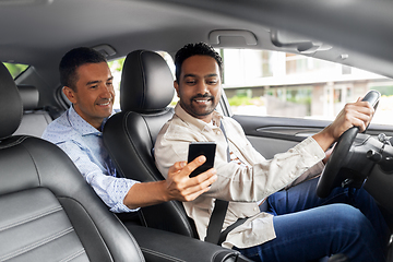 Image showing male passenger showing smartphone to car driver