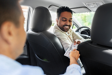 Image showing passenger giving money to smiling taxi car driver