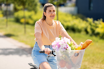 Image showing woman with food and flowers in bicycle basket