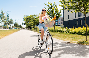 Image showing woman with food and flowers in bicycle basket