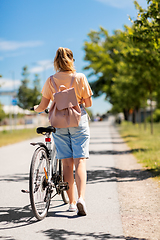 Image showing woman with bicycle and backpack walking in city