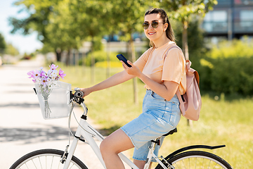 Image showing woman with smartphone on bicycle in city