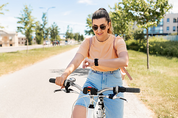 Image showing woman with smart watch riding bicycle in city