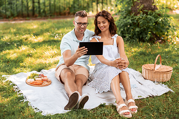 Image showing happy couple with tablet pc at picnic in park