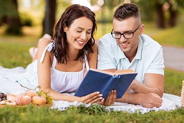 Image showing happy couple reading book on picnic at summer park
