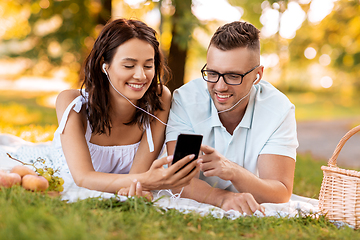 Image showing couple with earphones and smartphone at picnic