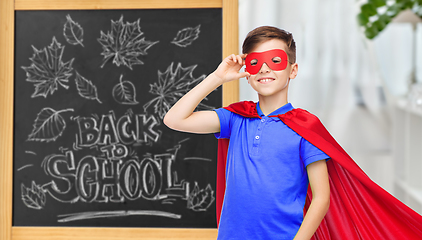 Image showing boy in super hero costume over school blackboard