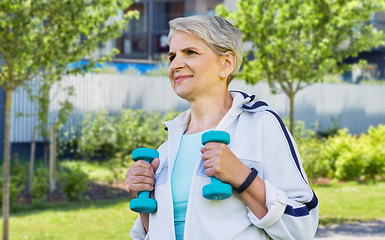 Image showing senior woman with dumbbells exercising in city