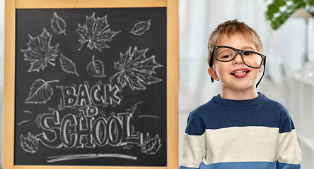 Image showing little student boy in glasses showing tongue