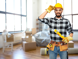 Image showing happy male builder in helmet with level at home