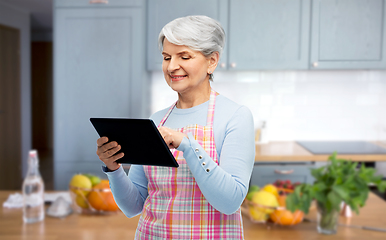 Image showing smiling senior woman in apron with tablet computer