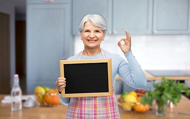 Image showing senior woman in apron with chalkboard showing ok