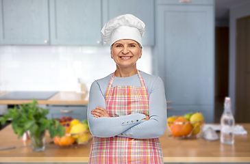 Image showing smiling senior woman or chef in toque at kitchen