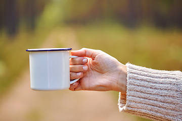 Image showing hand of woman with white tea mug in forest