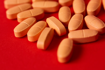 Image showing Pills spilling out of pill bottle on red. Top view with copy space. 