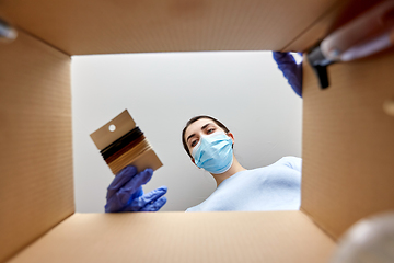 Image showing woman in mask unpacking parcel box with hair bands