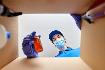 Image showing woman in mask packing parcel box with cosmetics