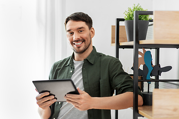 Image showing happy smiling man with tablet pc at shelf at home