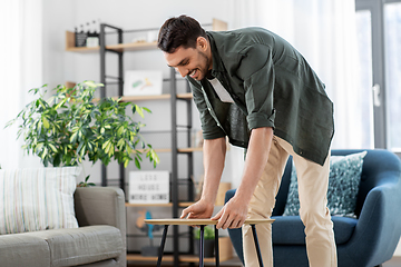 Image showing man placing coffee table next to sofa at home