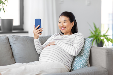 Image showing happy pregnant woman with smartphone at home