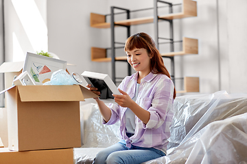 Image showing happy woman unpacking boxes and moving to new home