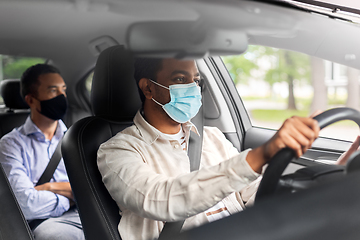 Image showing male driver in mask driving car with passenger