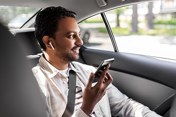 Image showing passenger with earphones and cellphone in taxi car