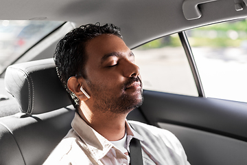 Image showing indian male passenger with earphones in taxi car