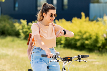 Image showing woman with smart watch riding bicycle in city