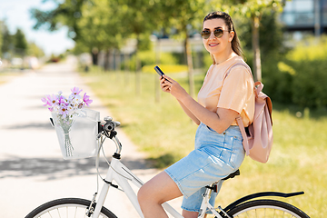 Image showing woman with smartphone on bicycle in city