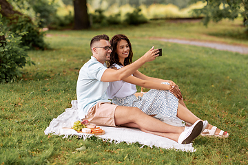 Image showing happy couple taking selfie at picnic in park