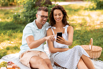 Image showing happy couple with smartphone at picnic in park