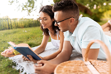 Image showing happy couple reading book on picnic at summer park