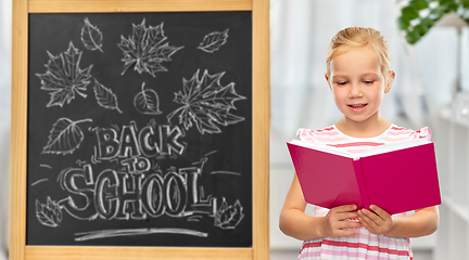 Image showing smiling little student girl reading book