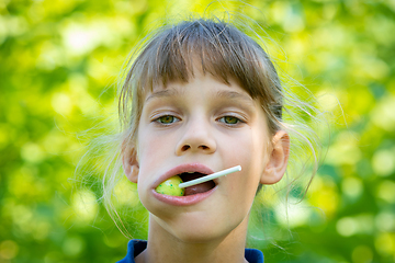 Image showing The girl has a big round lollipop in her mouth, close-up portrait