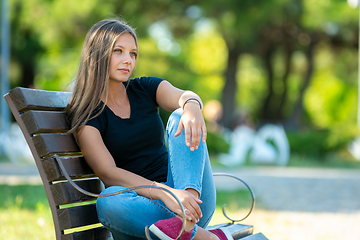 Image showing Girl sitting on a bench in the park, close-up