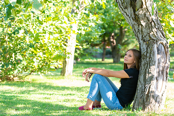 Image showing Girl sitting under a tree in a sunny park