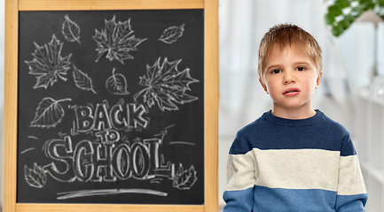 Image showing bored little student boy over school blackboard