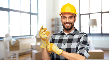 Image showing happy male builder in helmet and gloves at home