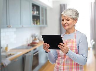 Image showing smiling senior woman in apron with tablet computer