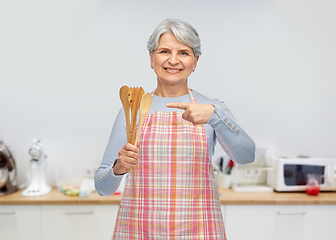 Image showing smiling senior woman in apron with wooden spoons